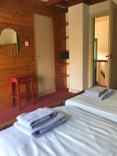 two beds in a room with towels on them at De Sloep in Bergen