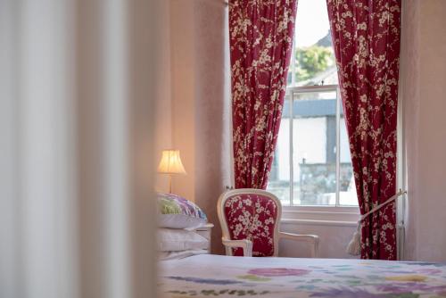 a bedroom with a bed and a window with red curtains at Barnes Fell Apartments in Ambleside