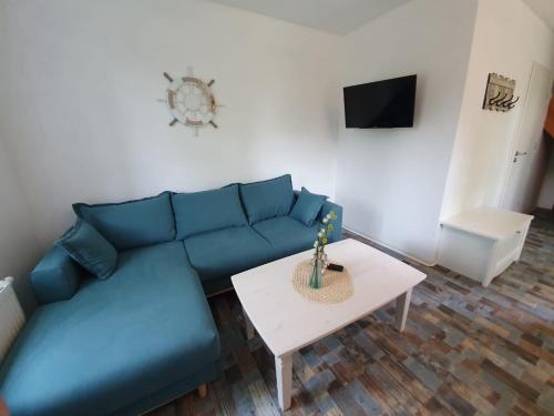 a living room with a blue couch and a table at Marijanas Ferienhof 2, Urlaub mit viel Platz zwischen Dornumersiel und Bensersiel, gehört zum Café Kunterbunt in Holtgast