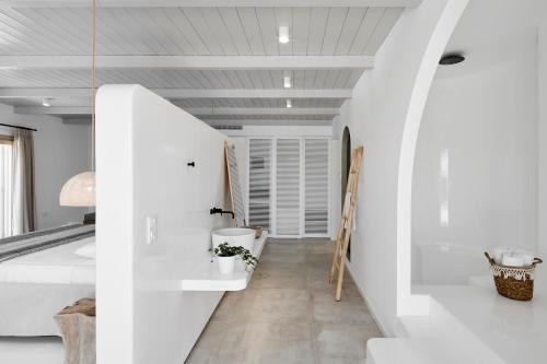 a bedroom with white walls and a white bed at Arco Solium Suites in Adamas