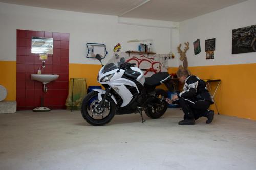 a man working on a motorcycle in a garage at Hotel-Pension Birkenhof in Kötschach
