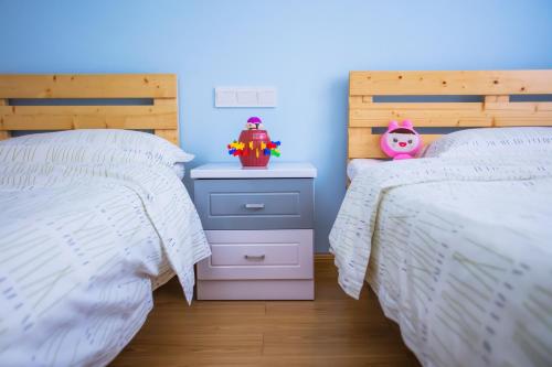 a bedroom with two beds and a nightstand with a toy at Murphy Youth Hostel Guilin桂林北站莫非青年旅舍 in Guilin
