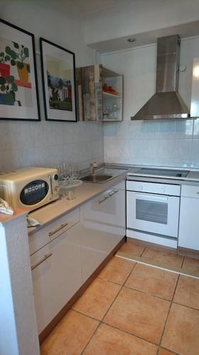 uma cozinha com armários brancos, um lavatório e um fogão em Suite Olivier em Saarbrücken
