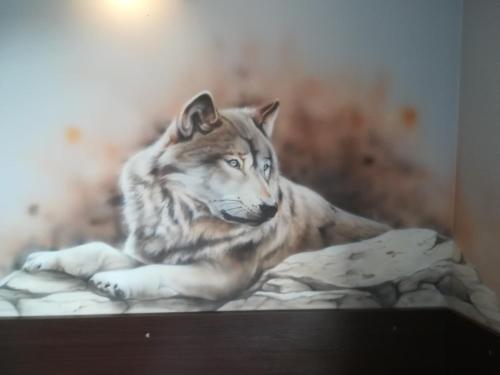 a painting of a wolf laying on a bed at Noclegi nad Soliną in Solina