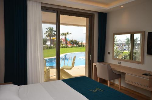 a hotel room with a bed and a desk and a pool at Almyros Beach in Acharavi
