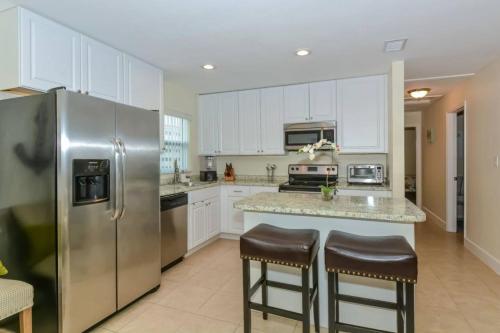 a kitchen with a stainless steel refrigerator and two bar stools at Lovely Cottage near the Beach and Downtown Sarasota in Sarasota