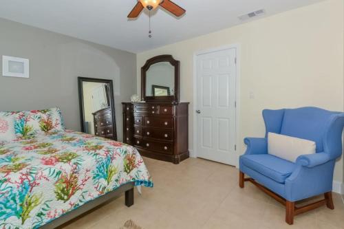 a bedroom with a bed and a blue chair and a mirror at Lovely Cottage near the Beach and Downtown Sarasota in Sarasota