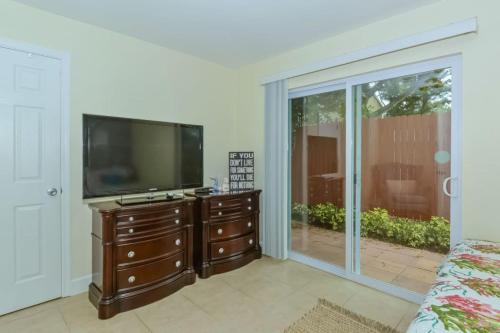 a living room with a flat screen tv on a dresser at Lovely Cottage near the Beach and Downtown Sarasota in Sarasota
