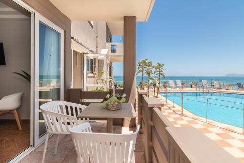 a balcony with a table and chairs and a swimming pool at Girogiali beach hotel in Stalos