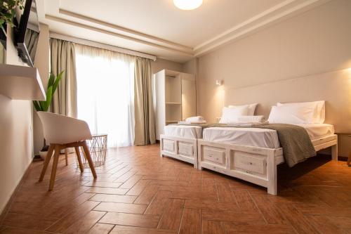 a bedroom with two beds and a table and a chair at Girogiali beach hotel - Adults only in Stalos