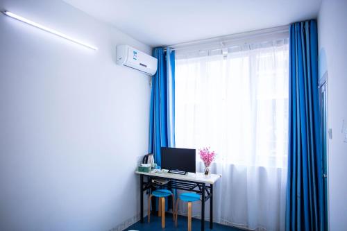 a room with a desk with a computer and blue stools at Murphy Youth Hostel Guilin桂林北站莫非青年旅舍 in Guilin