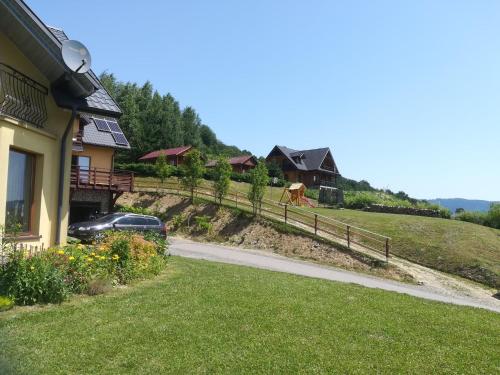 a house with a car parked next to a road at Noclegi nad Soliną in Solina