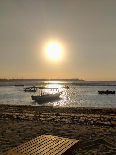 a boat on the beach with the sun in the sky at Salili Bungalow in Gili Air