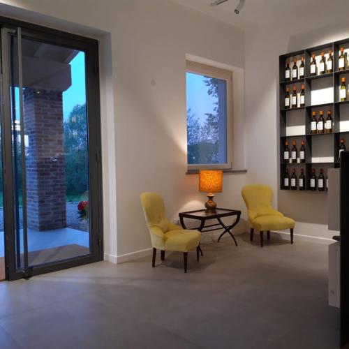 a room with two chairs and a table and wine bottles at Agriturismo Bacchanalis in Ziano Piacentino