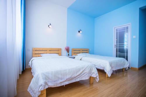 two beds in a room with a blue wall at Murphy Youth Hostel Guilin桂林北站莫非青年旅舍 in Guilin