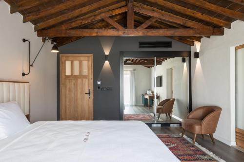 a bedroom with a white bed and a chair at Gillham Vineyard Hotel in Temblos