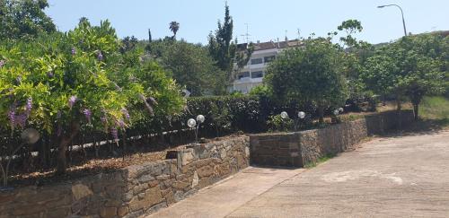a stone retaining wall with trees and a building at Delfini Hotel in Menídion
