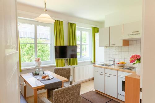 ゼーボーデンにあるHaus Elisabethのキッチン(緑のカーテン、テーブル、椅子付)