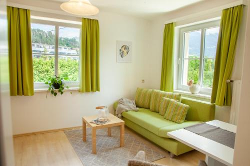 a living room with a green couch and windows at Haus Elisabeth in Seeboden