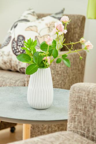 a white vase with pink flowers on a table at Haus Elisabeth in Seeboden