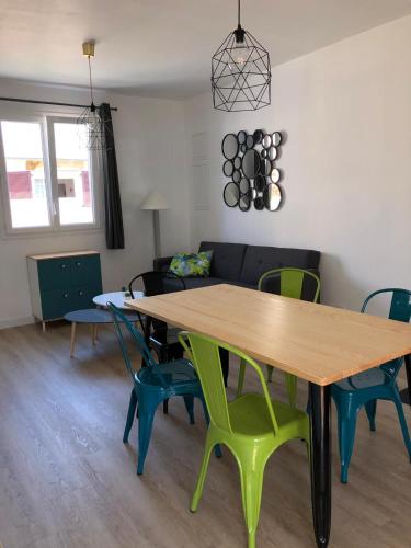 a dining room with a wooden table and green chairs at Maison design perros guirec, 2 à 4 personnes in Perros-Guirec