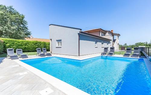 a swimming pool with chairs and a house at Toni & Julija in Poreč