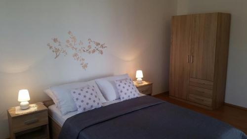 a bedroom with a bed with two night stands and two lamps at Apartman Ivanica in Jezera