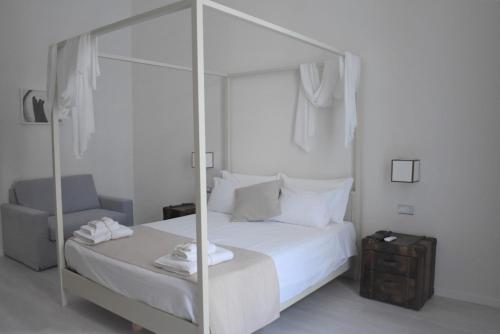 a white bedroom with a canopy bed and a chair at Gatto Bianco Duchessa in Bari