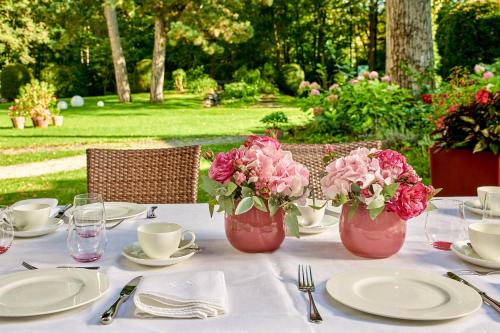 a table with plates and vases with pink flowers at Parkhotel Rothof in Munich