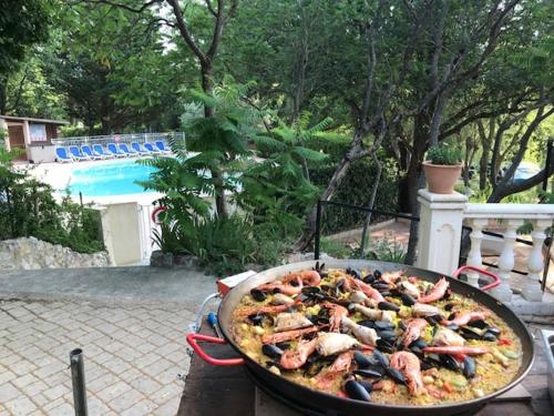 a pan of pizza with seafood on a grill at LES BASTIDES DE CHANTERAINE Bungalows, Lodges & Spa in Aiguines