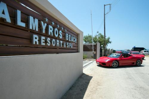 a red car parked in a parking lot at Almyros Beach in Acharavi