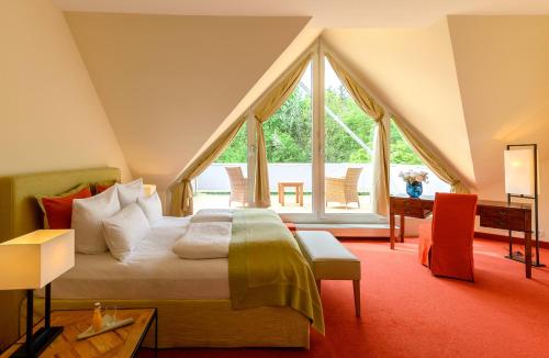 um quarto com uma cama e uma grande janela em Parkhotel Rothof em Munique