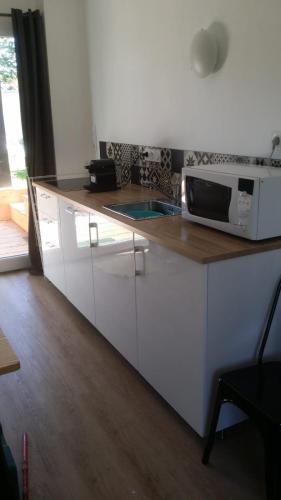 een keuken met witte kasten en een magnetron op een aanrecht bij Maison design perros guirec, 2 à 4 personnes in Perros-Guirec