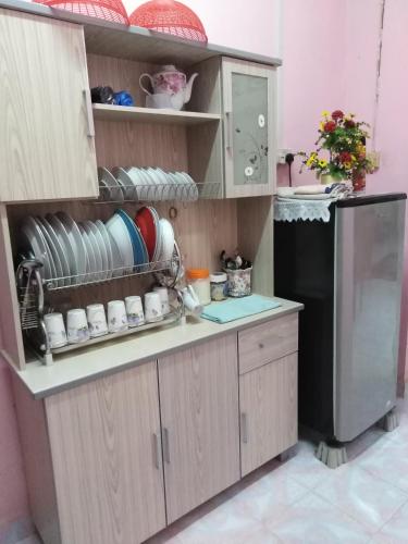 a kitchen with wooden cabinets and a black refrigerator at Homestay Haji Hamid in Pantai Cenang