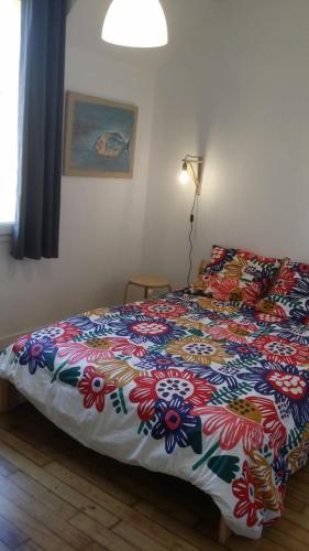 a bedroom with a bed with a colorful comforter at Maison design perros guirec, 2 à 4 personnes in Perros-Guirec