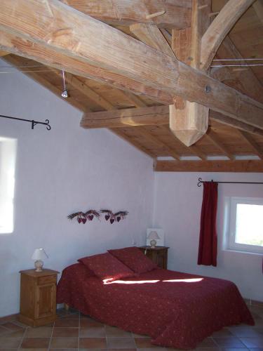 une chambre avec un lit avec un plafond en bois dans l'établissement La Bastide de Ninou maison de vacances Luberon, à Viens