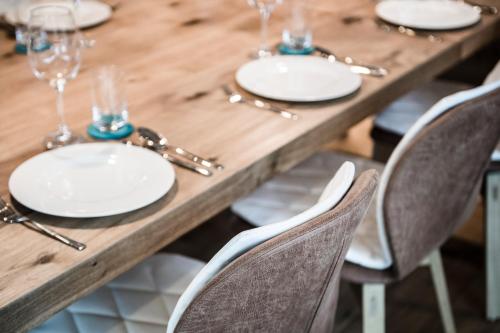 a wooden table with white plates and wine glasses at Chalet Ourtls Pärg in Solda