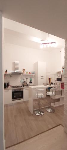 une cuisine avec des placards blancs, une table et des tabourets dans l'établissement Suite 332, à Cagliari