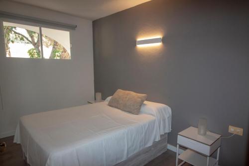 a bedroom with a white bed and a window at Apartamentos Portinatx Sea View in Portinatx