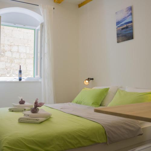 a bedroom with a bed with green sheets and a window at The Little Gem in Komiža