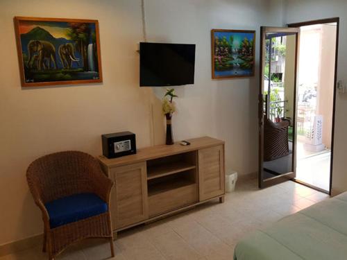 a bedroom with a television and a dresser with a chair at Oasis Guesthouse & Bar in Karon Beach