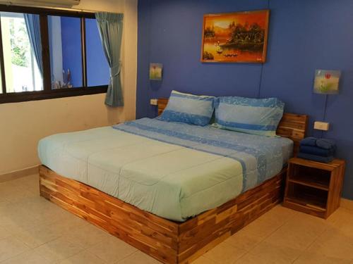 a bedroom with a wooden bed with blue walls at Oasis Guesthouse & Bar in Karon Beach