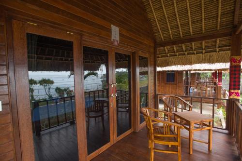 a room with a table and chairs on a balcony at Twilight Ceningan in Nusa Lembongan