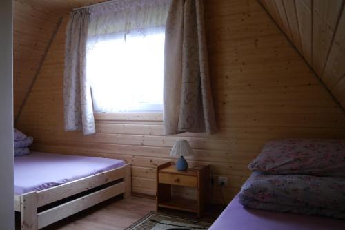 1 dormitorio con 2 camas y una ventana en una cabaña de madera en Leśniakówka 693-664-683, en Solina