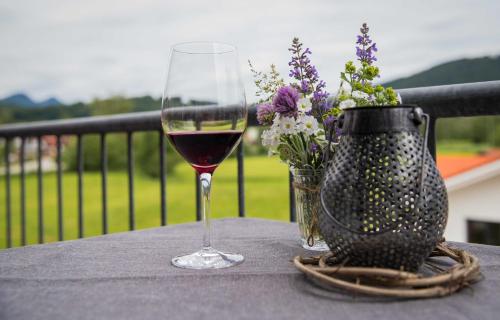 a glass of wine and a vase of flowers on a table at Ferienwohnung Traudl in Inzell