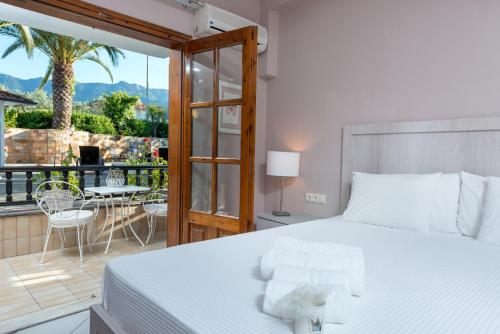 a bedroom with a bed and a balcony with a table at Villa Pipini Luxury Studios in Limenas