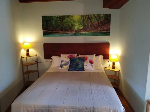 a bedroom with a large white bed with two lamps at El interior de Gaia in Arriondas