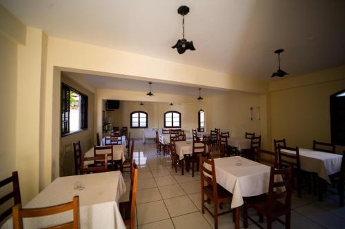 uma sala de jantar com mesas e cadeiras brancas e janelas em Hotel Casa Blanca em São Lourenço