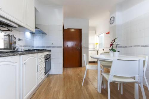 a kitchen with a table and white cabinets and a table and chairs at Charming Guesthouse - Sónias Houses in Lisbon