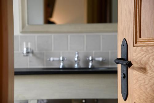 a bathroom door with a sink and a mirror at The Bell at Ramsbury in Marlborough